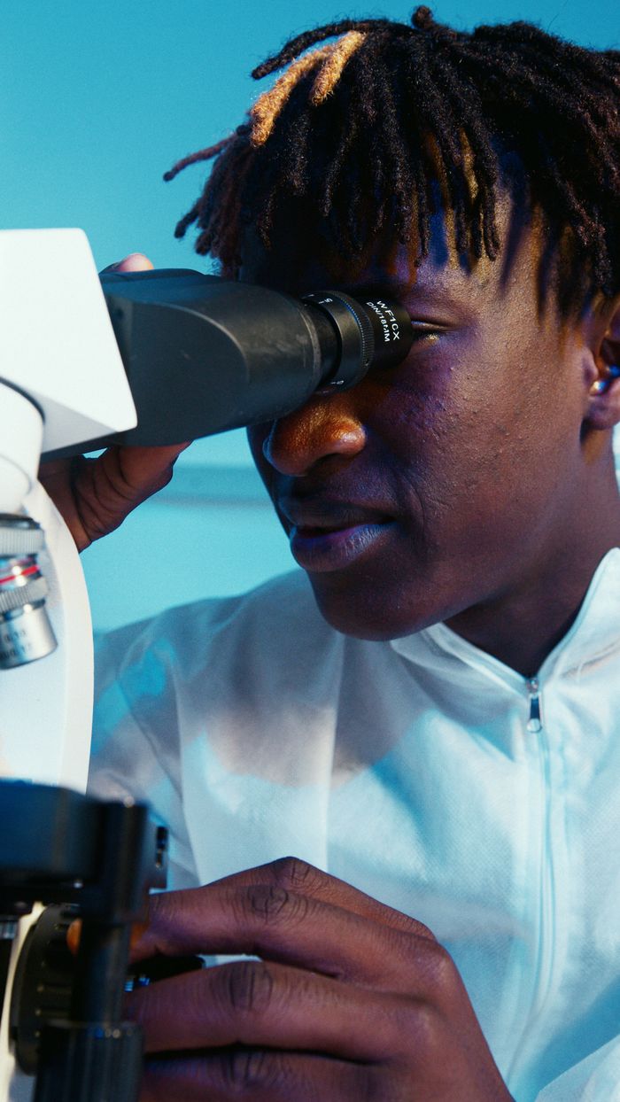 services-01 A young scientist examines samples using a microscope in a laboratory setting.